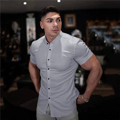 A man wears a light gray short-sleeved slim-fit button-down shirt with a collar.