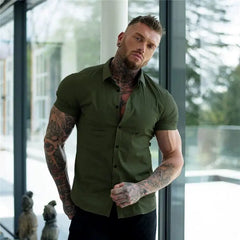 A man with tattoos wears a slim-fit, short-sleeved olive green button-down shirt.