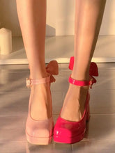 A pair of square-toe Mary Jane heels in two shades of pink, featuring ankle straps and back bows.