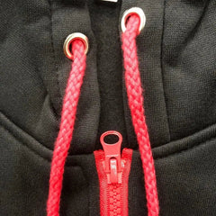 A close-up of a black zip-up hoodie featuring a bright red zipper and matching red drawstrings.