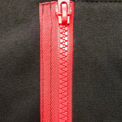 A close-up view of a red plastic zipper on a black fleece hoodie.
