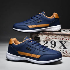 Men's Sneakers 2022: Stylish navy blue mesh shoes with orange accents and white soles, one lace-up sneaker laid flat and the other propped on a vintage-style box. Lightweight, anti-skid, breathable men's fashion sports shoes.