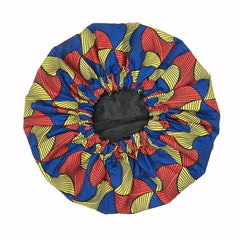 The New African Ankara Pattern Satin Lined Bonnet is a vibrant, double-layer headwrap with red, yellow, and blue wavy stripes. This big-size, multifunctional cap protects hair in style with its colorful gathered elastic design and long ribbon.