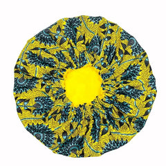The New African Ankara Pattern Satin Lined Bonnet features a bright yellow center and blue-black fish and leaf print on yellow fabric, perfect as a multifunctional skull cap or floral headscarf. Double layered with long ribbon for adults.