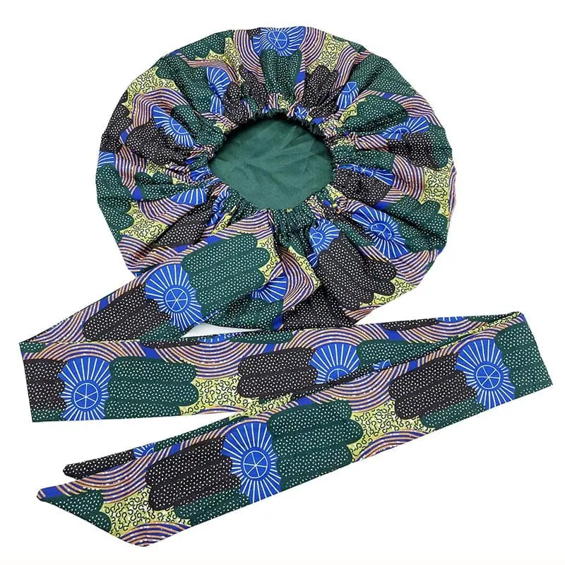 The New African Ankara Pattern Satin Lined Bonnet features an elastic opening and matching long ribbon headwrap with green, black, blue, and yellow geometric and floral designs. The big size adult hair cover is double layered for added protection.