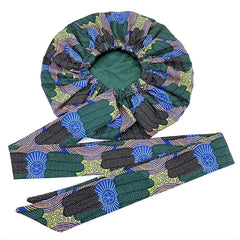 The New African Ankara Pattern Satin Lined Bonnet features an elastic opening and matching long ribbon headwrap with green, black, blue, and yellow geometric and floral designs. The big size adult hair cover is double layered for added protection.