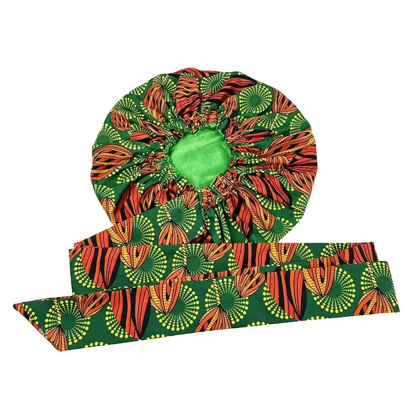 The New African Ankara Pattern Satin Lined Bonnet and Long Ribbon Headwrap features bold green, orange, yellow, and black leaf and circular designs on soft fabric. This double-layer headscarf offers big size adult hair cover.