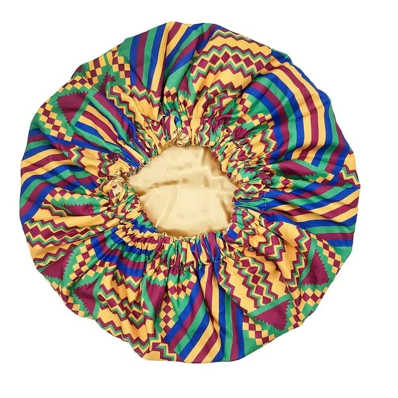 The New African Ankara Pattern Satin Lined Bonnet features a vibrant geometric print in yellow, green, red, and blue with zigzags and stripes. This big-size headscarf has a double layer, elastic edge, and long ribbon for a secure fit.