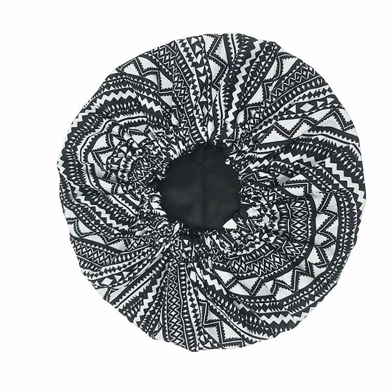 The New African Ankara Pattern Satin Lined Bonnet features a double-layer design, long ribbon headwrap, and geometric black-and-white prints. This big size hair cover for women is shown on a white background.