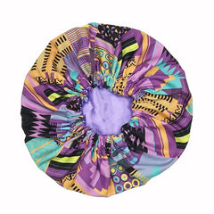 The New African Ankara Pattern Satin Lined Bonnet is a vibrant women’s headwrap with purple, yellow, green, and black geometric patterns, a gathered elastic opening, light purple inner lining, and long ribbon ties.