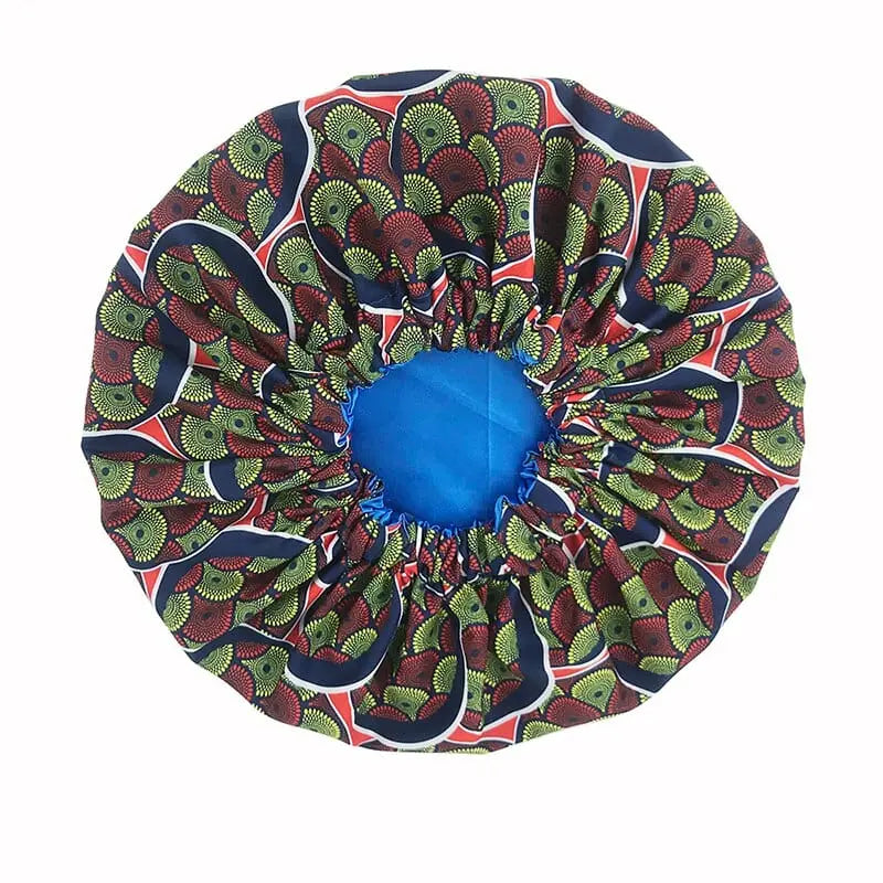 The New African Ankara Pattern Satin Lined Bonnet features a green, red, and black patterned outer layer with a solid blue satin inner lining. This double-layer headscarf has a gathered elastic edge and long ribbon for comfort—ideal as a women’s beanie or headwrap.