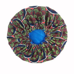 The New African Ankara Pattern Satin Lined Bonnet features a green, red, and black patterned outer layer with a solid blue satin inner lining. This double-layer headscarf has a gathered elastic edge and long ribbon for comfort—ideal as a women’s beanie or headwrap.