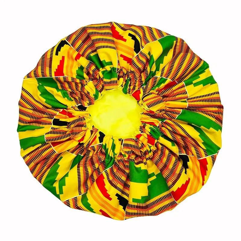 The New African Ankara Pattern Satin Lined Bonnet features a vibrant kente-inspired yellow, green, red, and black design, a gathered center with stretchy band, and a long ribbon headwrap for adult hair coverage.