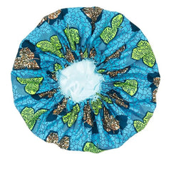 The New African Ankara Pattern Satin Lined Bonnet is a big-size women’s headscarf with green and brown leafy designs, black outlines, and an elastic band. It features a long ribbon and double-layer satin lining, shown on a white background.