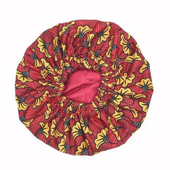 The New African Ankara Pattern Satin Lined Bonnet is a big-size women’s hair cover featuring a vibrant yellow and black floral design on red, with an elastic opening and long ribbon headwrap for secure, stylish wear.