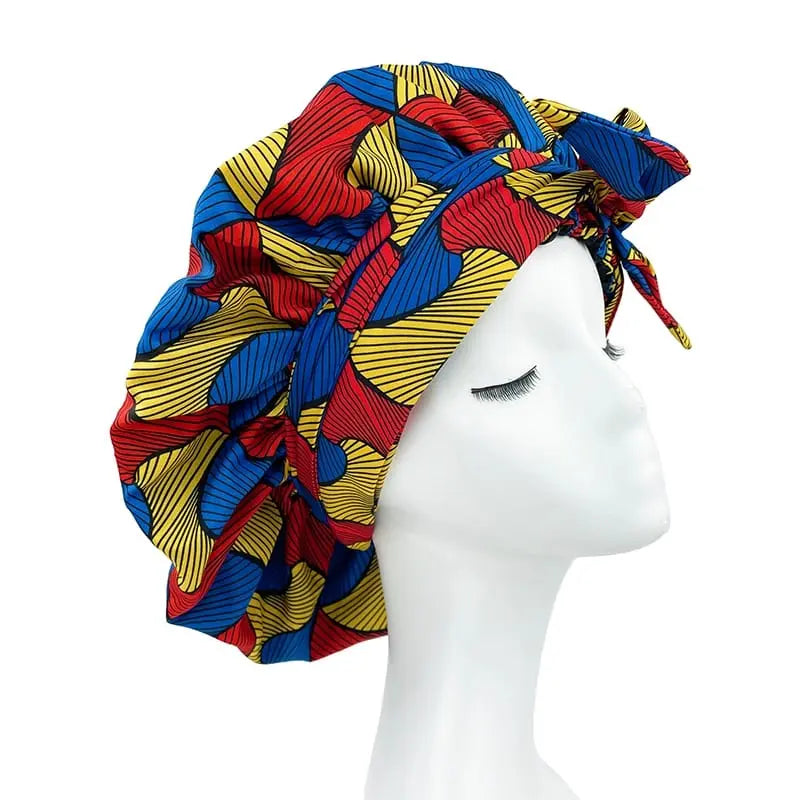 A mannequin head displays the New African Ankara Pattern Satin Lined Bonnet—a vibrant, double-layer headwrap with long ribbons, big size, and colorful abstract design—ideal as a stylish adult hair cover or multifunctional skull cap.