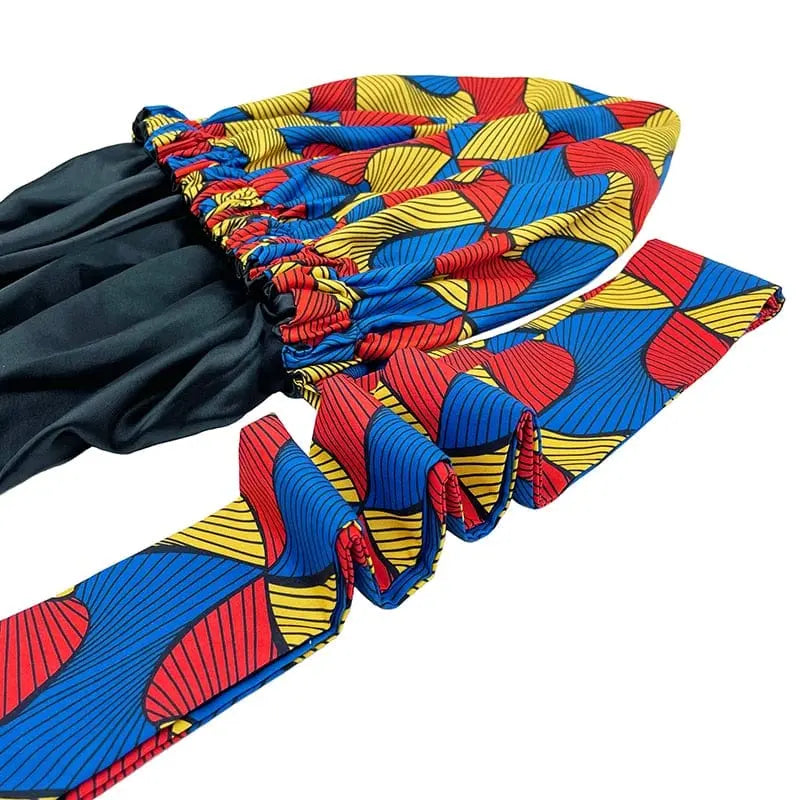 The New African Ankara Pattern Satin Lined Bonnet is a big size, double-layer headscarf for women. It features vibrant red, blue, and yellow patterns with black lining and long ruffled ribbons for a comfortable, stylish fit.