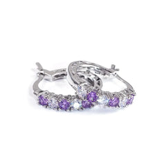 A pair of silver hoop earrings featuring alternating purple and clear round cubic zirconia stones.