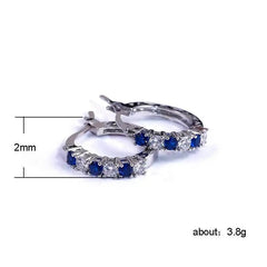 A pair of sterling silver hoop earrings featuring alternating blue and clear round zircon stones.