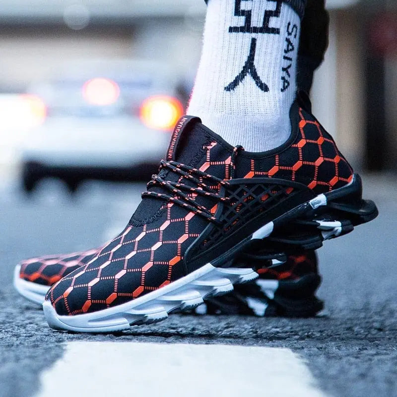 A close-up of a person wearing New Fashion Men Running Shoes Sports Shoes Casual Trainers with black mesh, orange hexagonal pattern, and chunky soles. Styled with white socks, they stand on a city street in these trendy men's sneakers.