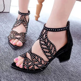 Black faux leather sandals with rhinestone-studded cutouts, a thick square heel, and back zipper.