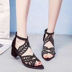 Black faux leather sandals with rhinestone embellishments, a hollow-out design, and a block heel.