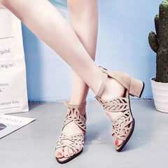 A pair of beige faux leather sandals with a hollow-out design, rhinestones, and a thick heel.