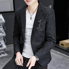 A man wears a black slim-fit casual blazer with a textured pattern and a decorative lapel pin.
