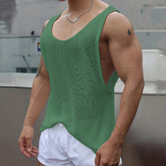 A man wears a loose-fitting, green knitted V-neck tank top with wide armholes.