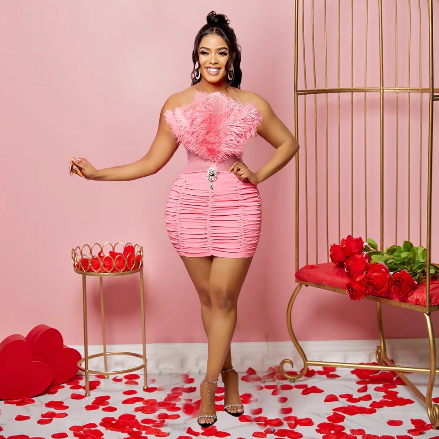 A woman wears a pink sleeveless tube top dress featuring a feathered bodice and ruched skirt.