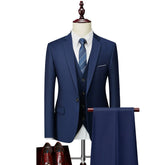 A navy blue slim-fit three-piece suit with a white shirt and tie displayed on a mannequin.