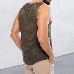 A man wears a loose-fitting, olive green knitted V-neck tank top with a textured finish.