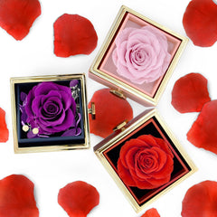 Three square jewelry boxes containing preserved purple, pink, and red roses on a white background.