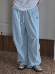 A person wears light blue, loose-fitting, quick-dry pants with a drawstring waist and a small logo.