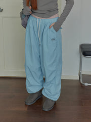 A person wears light blue, loose-fitting, quick-dry outdoor pants with a small logo on the hip.