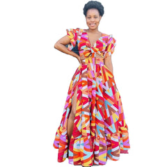 A woman wears a colorful, geometric-print maxi dress with a tie-front bodice and a side slit.