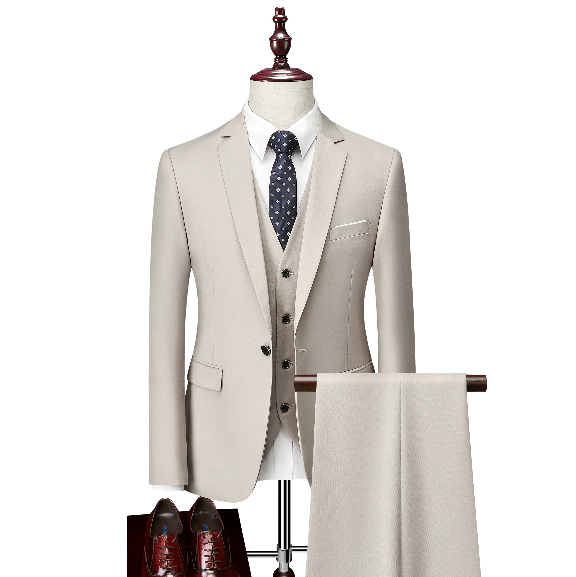 A beige slim-fit three-piece suit with a white shirt, dark patterned tie, and brown dress shoes.