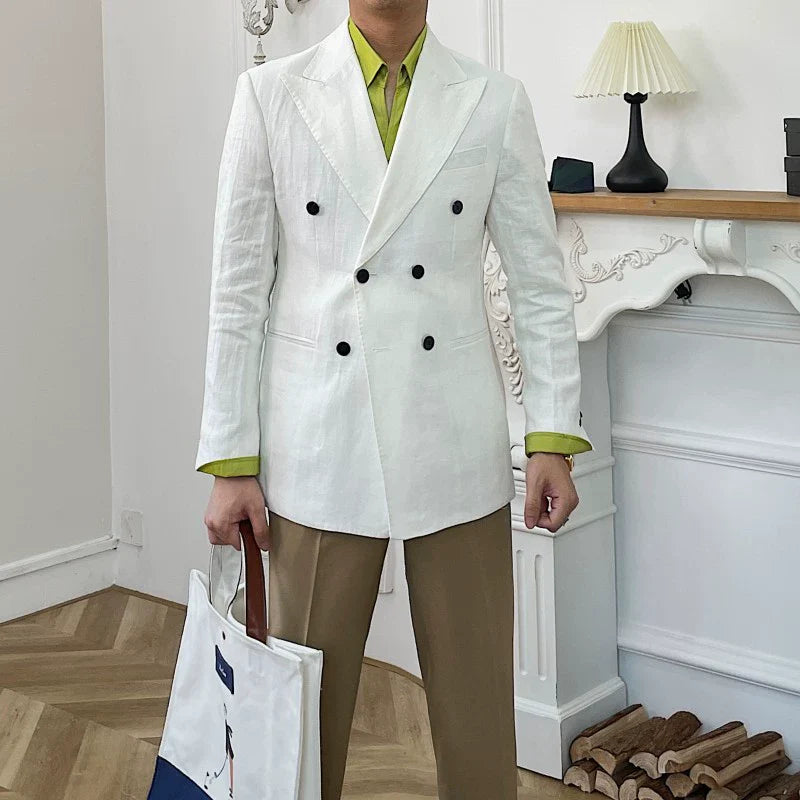 A man wears a white double-breasted linen suit jacket over a lime green shirt and tan trousers.