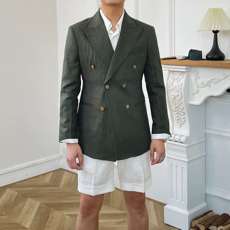 A man wears a dark green double-breasted linen suit jacket with white shorts.