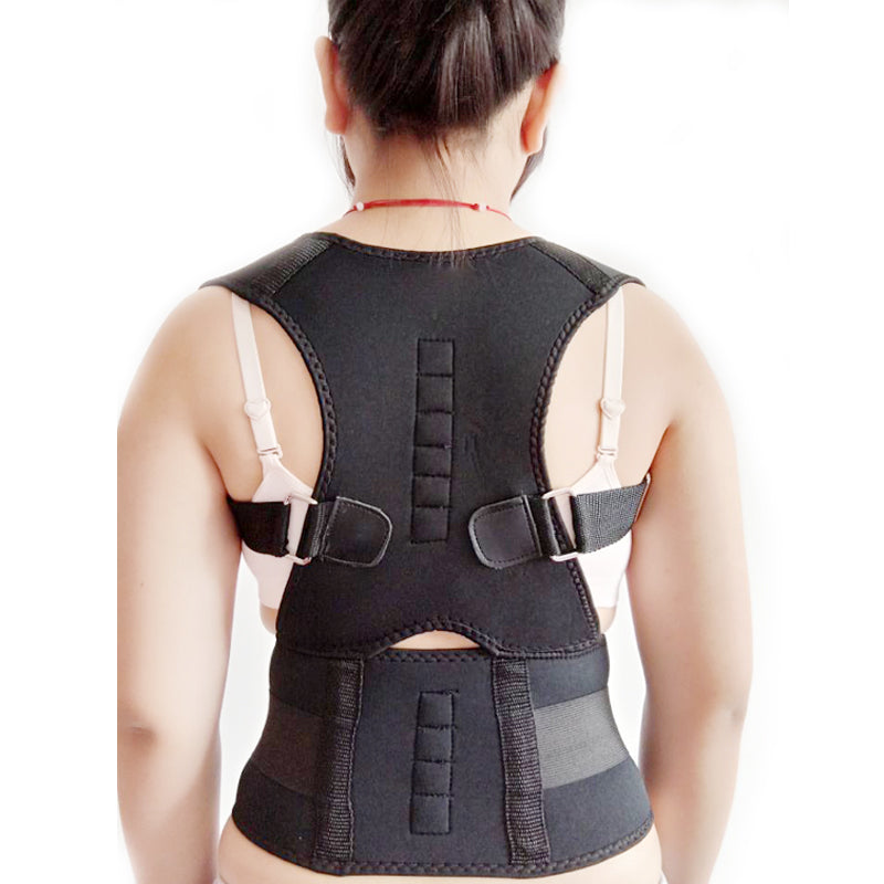 A person wearing a black posture corrector brace with adjustable straps and back support.