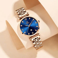 A rose gold stainless steel watch with a blue dial, crystal markers, and a date display.