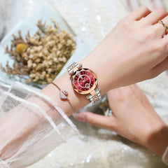 A woman wears a rose gold and silver stainless steel POEDAGAR watch with a red diamond-accented dial.