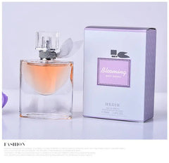 A 30ml bottle of Blooming pour femme perfume next to its purple and white box.