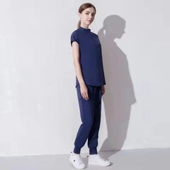 A woman wears a navy blue medical scrub set featuring a short-sleeved top and jogger-style pants.