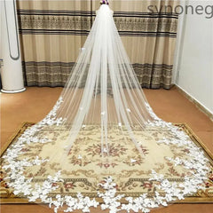 A long, single-layer cathedral wedding veil with white lace applique edges and a comb.