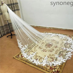 A long, single-layer cathedral wedding veil with white lace applique edges on a mannequin.