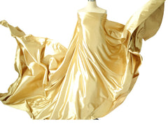 A mannequin displays a long, flowing piece of shiny gold satin fabric used for photography props.