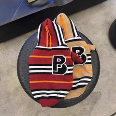 Two hooded pet sweaters with striped patterns and a large letter B patch on the back.