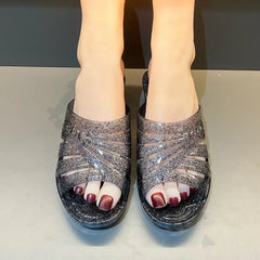 A pair of women's black glittery jelly wedge sandals with a cut-out design.