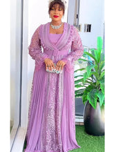 A woman wears a long-sleeved, lavender lace maxi dress with a matching belt and pleated skirt.